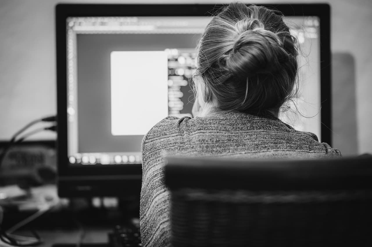 Une personne travaille sur un écran d'ordinateur, en train d'examiner un document sur un moniteur de bureau