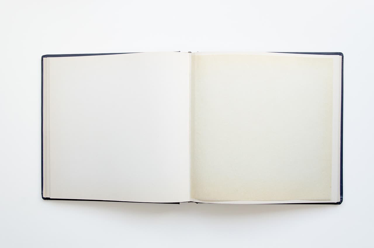 Um álbum de fotografias aberto em duas páginas completamente vazias, sobre fundo branco